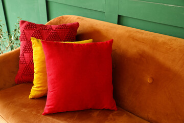 Red sofa with stylish cushions near green wall, closeup
