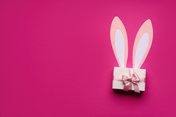 Paper bunny ears and gift box on pink background