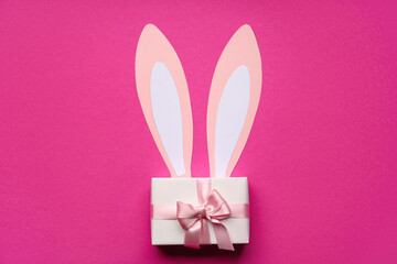 Paper bunny ears and gift box on pink background