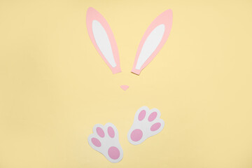 Paper bunny ears and paws on yellow background