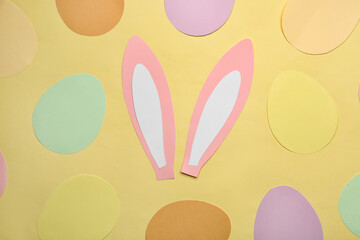 Paper bunny ears and Easter eggs on yellow background