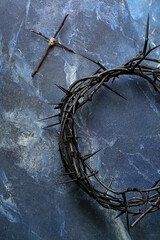Crown of thorns with wooden cross on blue grunge background. Good Friday concept