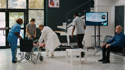 Father carrying unconscious kid in facility lobby to receive help from specialist, worried parents waiting to do emergency consultation with physician. Medic consulting sick girl in lobby.
