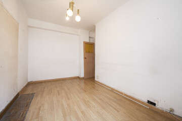 Empty room of a house with wooden floors and a lamp with three glass shades