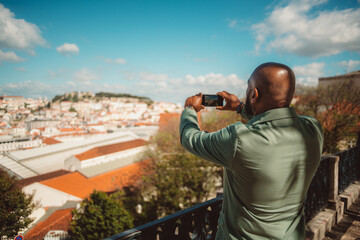 Capture in selective focus of a bald, bearded black tourist male from behind in a green suit jacket...