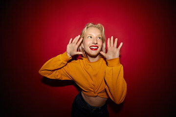 A happy girl posing isolated on red background and laughing.