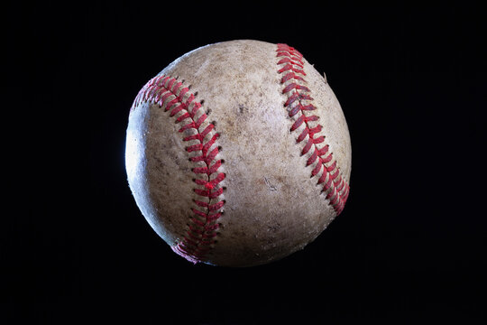 Old rough baseball with dramatic lighting isolated on a black background