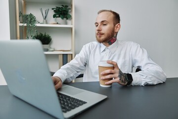 A man in a wheelchair, a businessman with tattoos in the office at a laptop, a coffee break,...