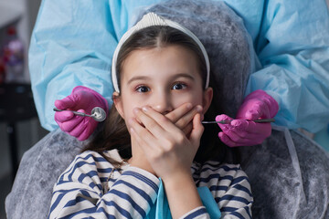Close up view of a little girl looking scared and terrified screaming covering her mouth from the...