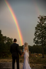 Bride and groom on wedding day looking at a rainbow