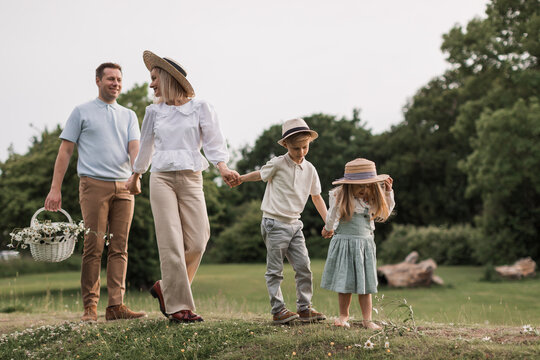 Children, dad and mom play in meadow in sunshine. mother, father and little daughter with brouther walking in field in the sun. Happy young family. concept of a happy family.