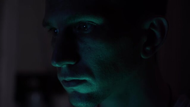 Portrait of a male hacker. nervous look. close-up. dark room