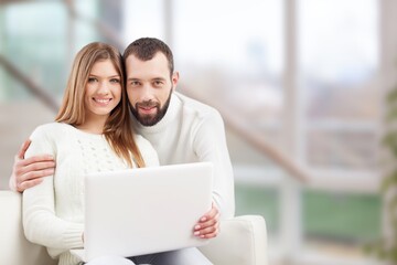 Young happy couple sitting with laptop computer