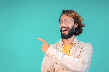 Confident young man pointing aside with finger hand gesture at copy space isolated color background