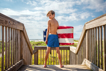 Young Preteen Boy Standing on Boardwalk with Boogie Board at the Beach