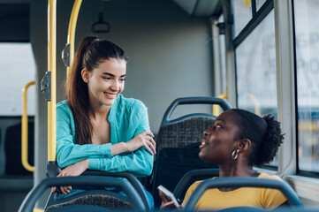 Multiracial friends talking while riding a bus in the city