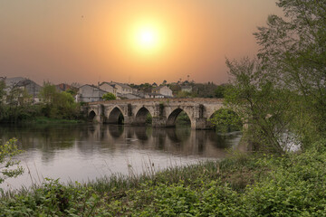 Spectacular sunset overlooking the Roman bridge and the river Miño as it passes through Lugo with...