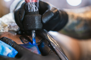 tattoo artist coloring in blue ink the tattoo, detail view