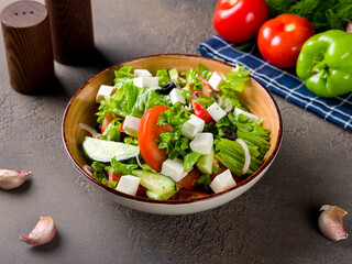 Greek salad with feta and fresh vegetables, olive oil and red onion on brown table