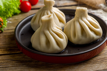 Khinkali with lamb on black plate on wooden table macro close up