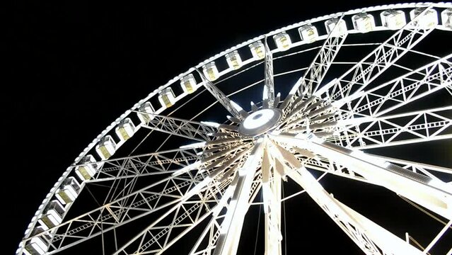blinking led illumination on giant attraction illuminated with bright led light on dark black sky, large white metal ferris wheel with small cabin heap, modern entertainment diversity