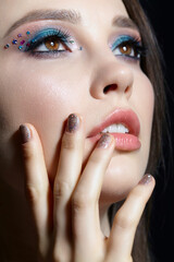 Close-up portrait of beautiful brunette with blue eye shadow make up and rhinestones.
