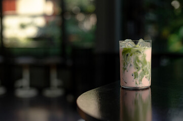 Strawberry Matcha Latte on a table with cream being poured into it, showcasing its texture.