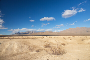 Desert with mountain background and blue sky with white clouds