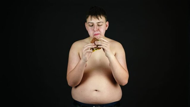 Young Fat Man Naked to Waist Eating Junk Fast Food, Overweight in Youth and Bad Diet Concept