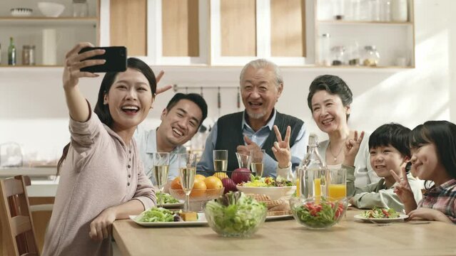 happy asian three generation family taking a selfie during while eating meal together at home