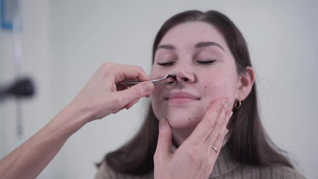 Professional female doctor otorhinolaryngologist doing nose examination with otoscope in modern hospital. Nasal congestion, sinusitis, allergy concept. Woman ENT doctor and patient in office clinics.