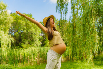 Obraz premium Pregnant woman happy excited in sustainable forest nature outdoors with open arms in freedom. Health, eco-friendly environment conservation concept. Pregnancy portrait