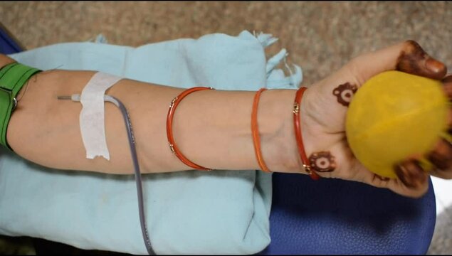 Blood donor at Blood donation camp held with a bouncy ball holding in hand at Balaji Temple, Vivek Vihar, Delhi, India, Image for World blood donor day on June 14 every year, Blood Donation Camp