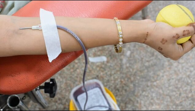 Blood donor at Blood donation camp held with a bouncy ball holding in hand at Balaji Temple, Vivek Vihar, Delhi, India, Image for World blood donor day on June 14 every year, Blood Donation Camp