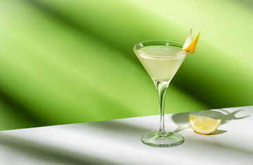 Vesper, classic alcoholic cocktail drink with dry gin, vodka, aperitif, lemon zest and ice. Light green background, hard light, shadow pattern