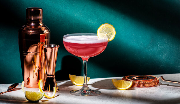 Pink Lady Alcoholic Cocktail Drink With Gin, Grenadine Syrup, Lemon Juice And Egg White, Dark Green Background, Bright Hard Light And Shadow Pattern