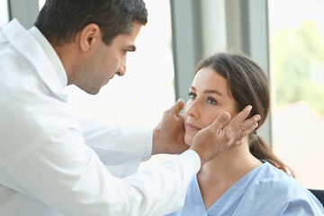 Fototapeta premium A doctor is examining the eyes of a young woman patient.