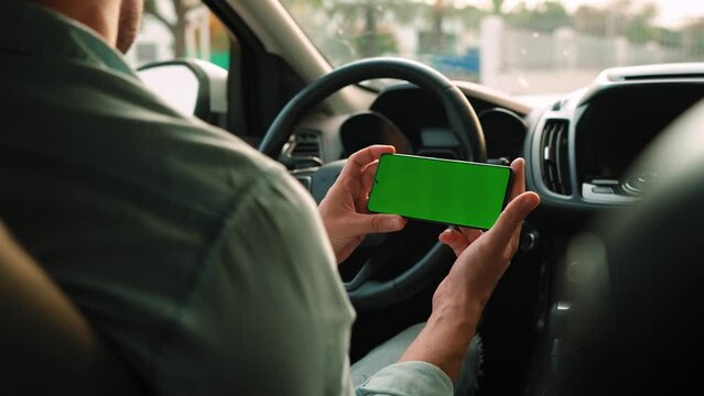 Male driver using a smartphone inside the car. Chromakey smartphone with green