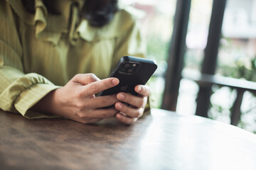Young woman using phone and computer to make online purchases in shop cafe
