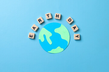 Top view of earth day lettering on square box surround globe made from paper isolated on blue background. World earth day concept. 