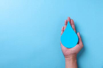World Water Day, save the water. Hands holding paper water drop on blue background, top view with...