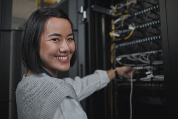 Asian woman, portrait smile and technician by server for networking, maintenance or systems at...