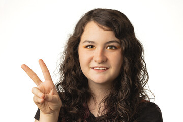 young brunett woman making a peace sign, on white background.