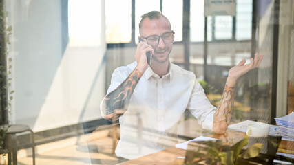 Fototapeta premium Professional Caucasian businessman on the phone with business client at his desk, dealing business