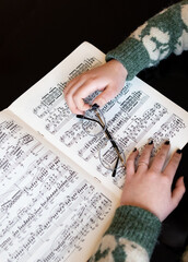 Hands of a girl with glasses on piano sheet music