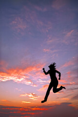 Fototapeta na wymiar 夕日を背景に走る若い女性のシルエット