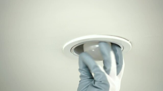 Close up electrician installing led light bulbs at home for power saving. Fixing changing the Light Inside apartment. Home service concept.