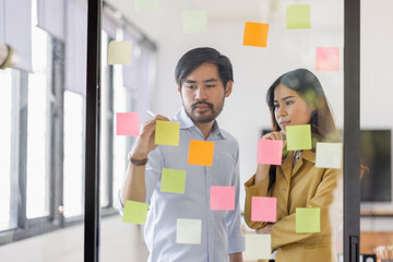 Team of Business female employee with many conflicting priorities arranging sticky notes commenting...