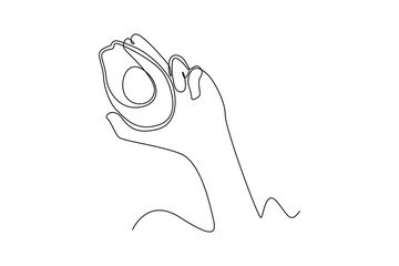 Continuous one line drawing hand holding avocado fruits. Healthcare at home concept. Single line draw design vector graphic illustration.