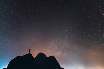 Silhouette of success young traveler raised hands watched the star and milky way alone on top of...